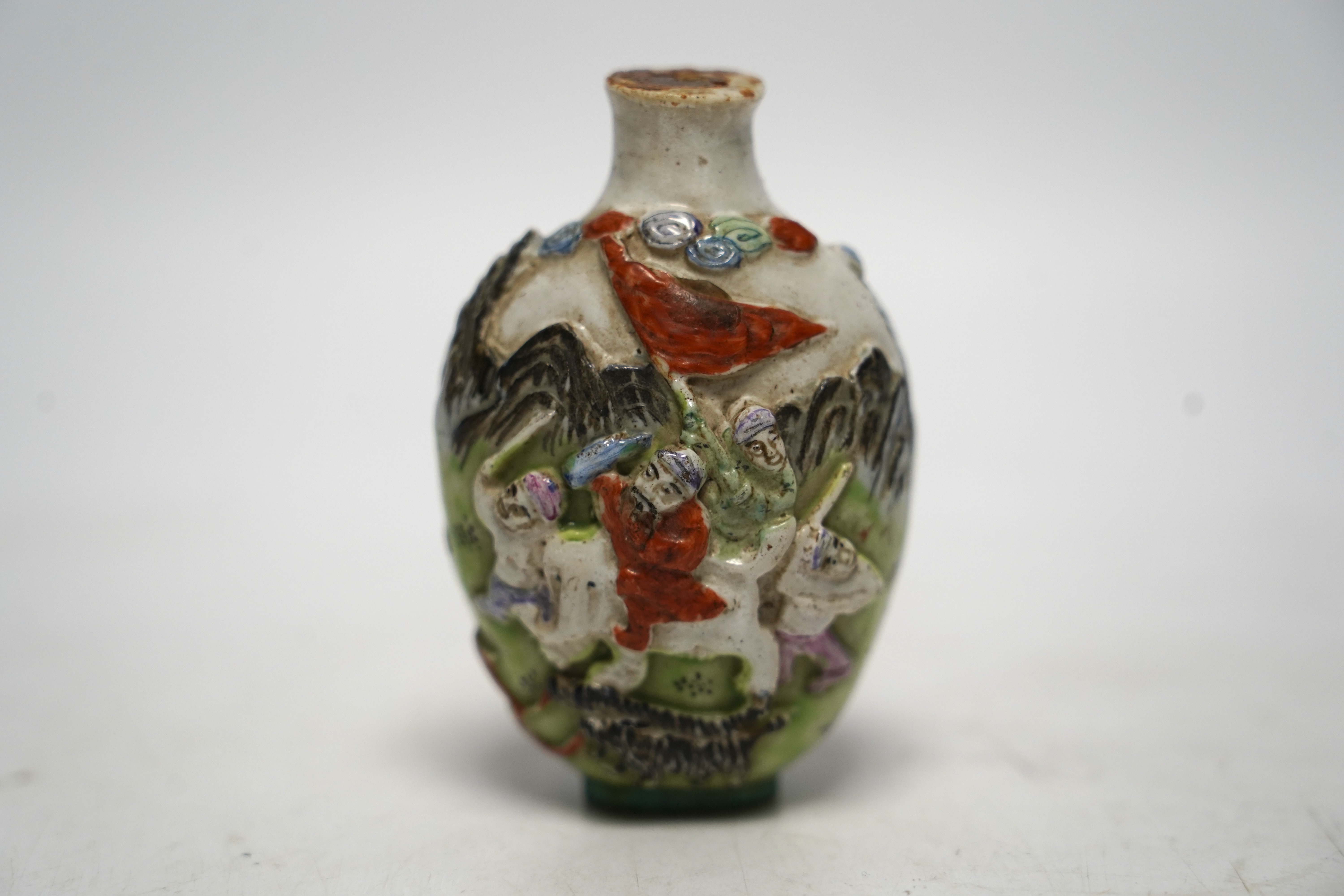 A Chinese moulded in enamelled porcelain ‘figures riding mythical beasts’ snuff bottle, Qianlong mark, 19th century, 8.5cm high